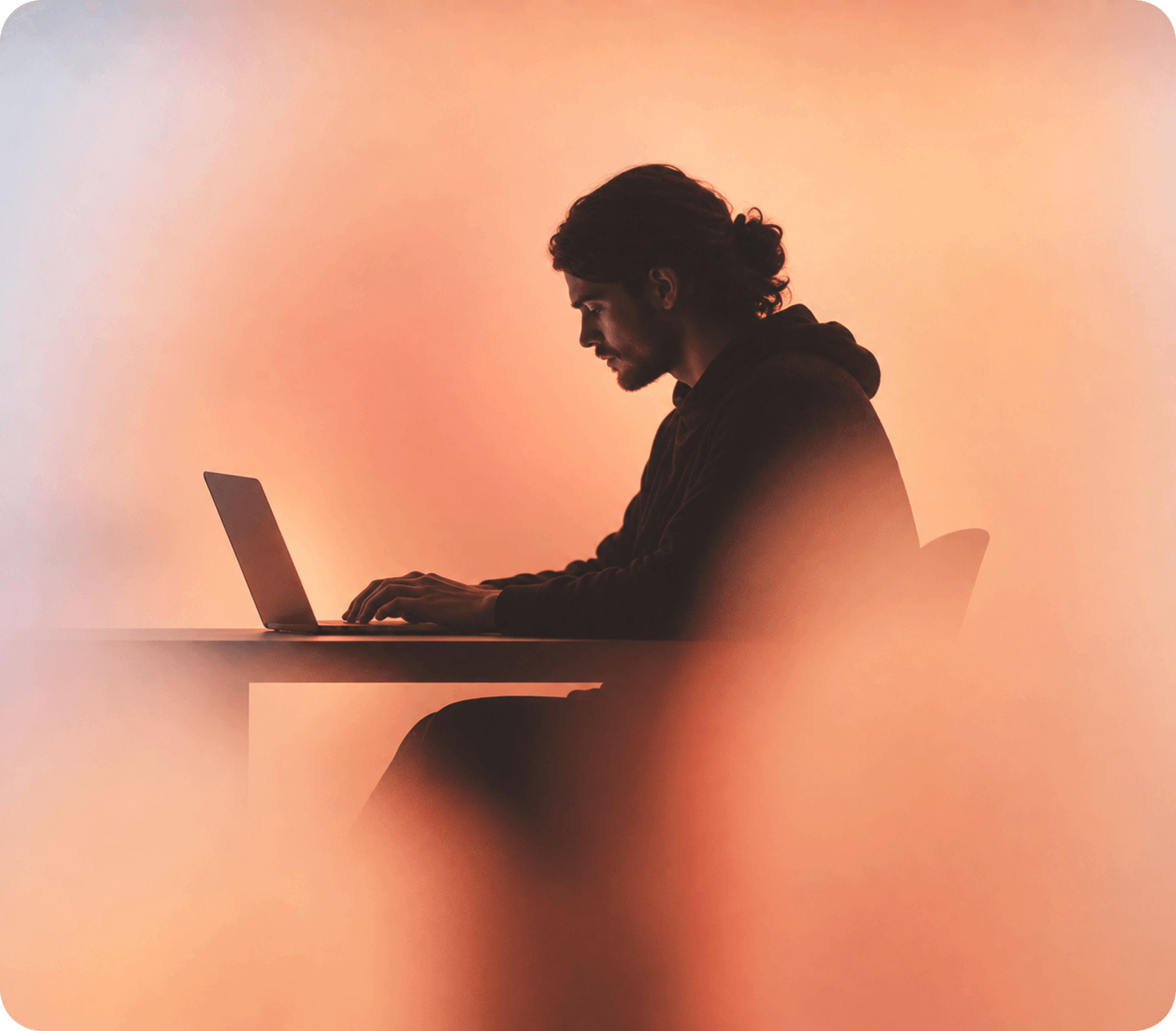 Person using a laptop against a warm orange background