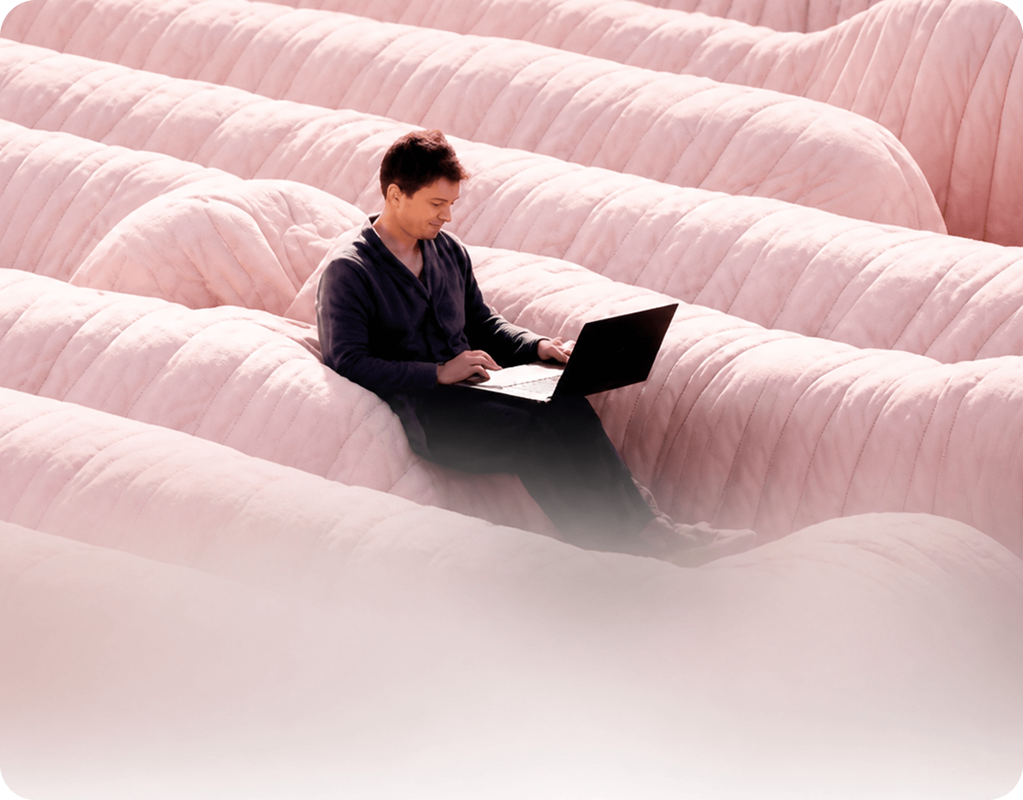 Person working on a laptop on a soft pink sofa